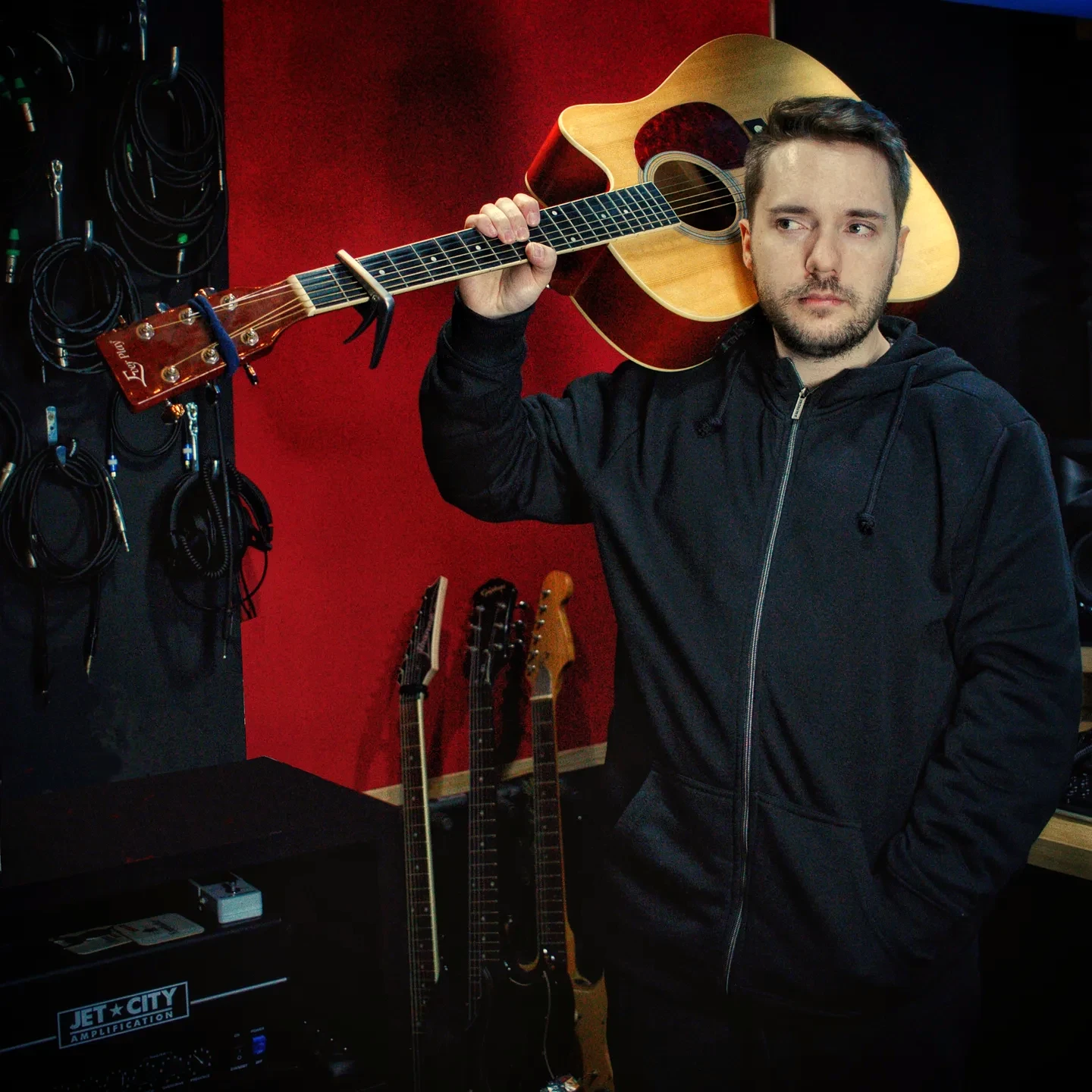 Dawid Mateja, realizator dźwięku i gitarzysta, z gitarą akustyczną w Pulsar Studio